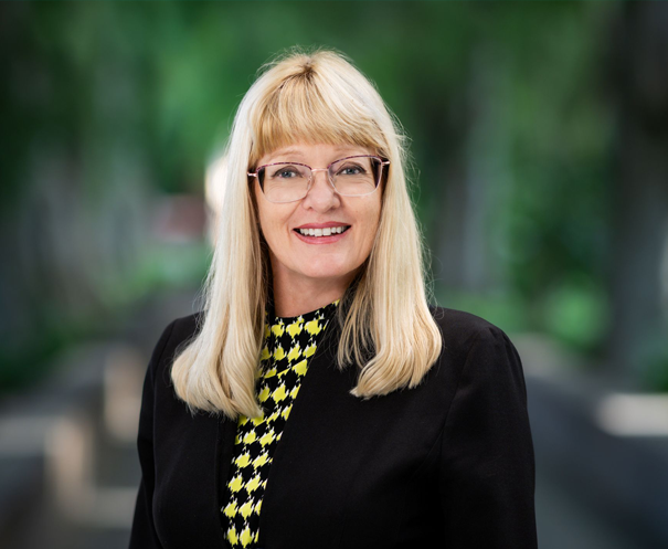 Lady wearing black jacket in gardens in background